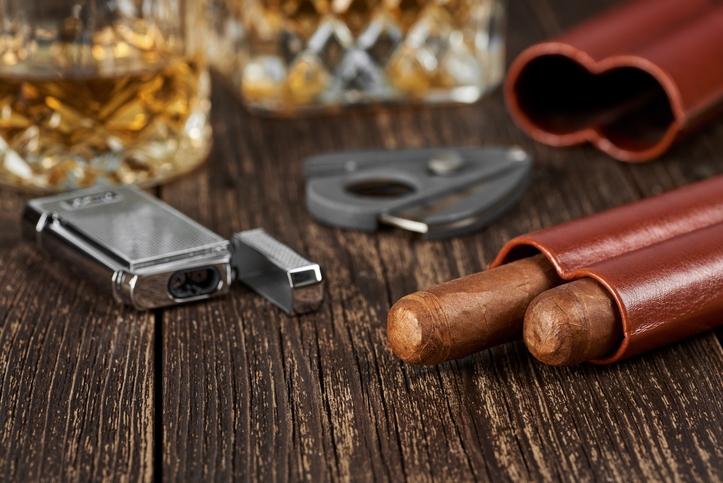 Two Cuban cigars, a cutter and a lighter in a leather case on an old brown table